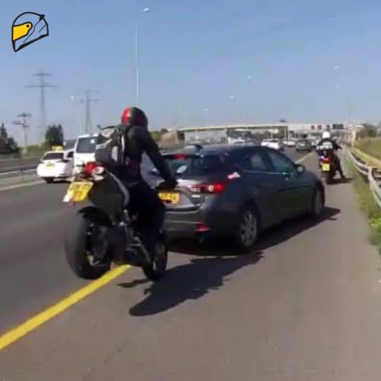 דיבורית בקסדה ורכיבה על אופנוע בשוליים